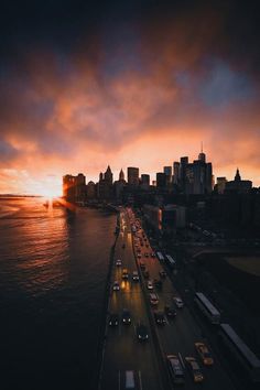 an aerial view of a city at sunset with cars driving on the road in front of it