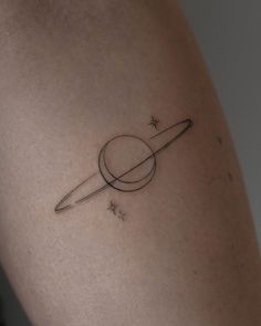 a small saturn tattoo on the back of a woman's right arm, with stars around it