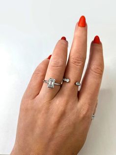 a woman's hand with two rings on her fingers and an orange nail polish