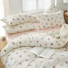 a bed with pink and white flowers on it, next to a window in a bedroom