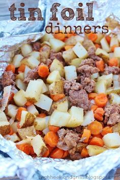 tin foil with meat, potatoes and carrots in it sitting on a wooden table