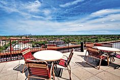 an outdoor patio with tables and chairs overlooking the city