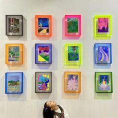 a person sitting in front of a wall with many different colored pictures on it's walls