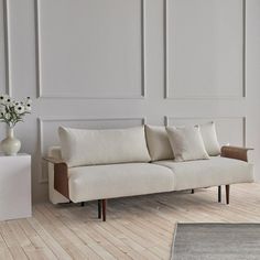 a white couch sitting on top of a wooden floor next to a vase filled with flowers