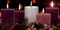 three lit candles surrounded by christmas decorations