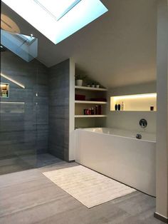 a bathroom with a skylight above the bathtub and shelves on the wall next to it