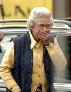 an older woman covers her mouth as she walks down the street