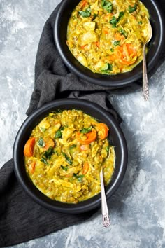 two black bowls filled with food on top of a table