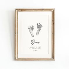 a baby's hand and foot prints are displayed in a wooden frame on the wall