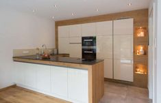 an empty kitchen with white cabinets and wood flooring on the walls, along with a black counter top