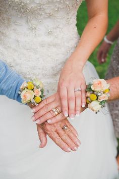 two brides holding hands with flowers on their fingers