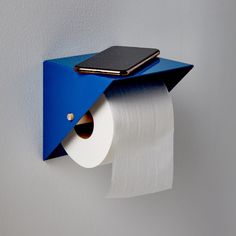 a cell phone is sitting on top of a toilet paper holder that has a blue cover over it