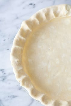 an uncooked pie crust on a marble counter top