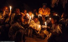 a group of people sitting around each other holding candles