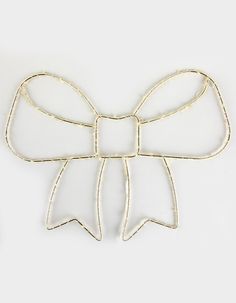 a gold metal bow brooch on a white background