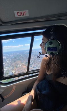 a woman sitting in the cockpit of an airplane looking out at the city from above