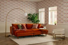 an orange couch sitting in a living room on top of a hard wood floor next to a white chair