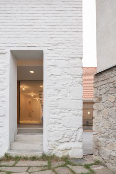 an open door to a white brick building with grass in the foreground and stone steps leading up to it