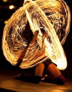 a woman is doing some kind of dance with fire in her hands and hair blowing around her