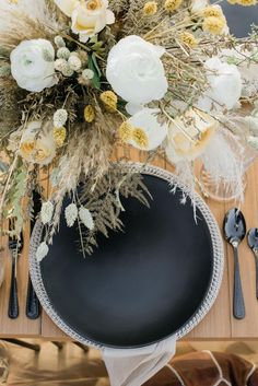 a black plate with white flowers on it next to silverware and utensils