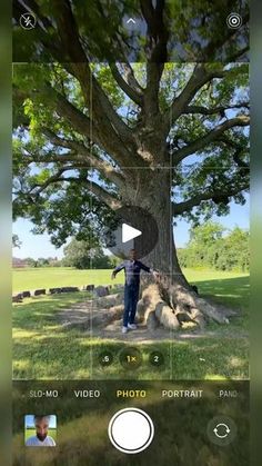 a person standing in front of a tree with their hands on the camera's lens