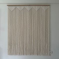 a wall hanging made out of string and wood sticks in a room with white walls