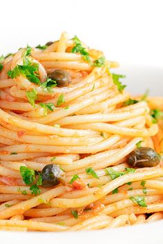 a white plate topped with pasta and olives