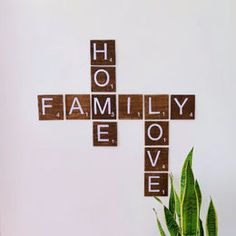 a cross made out of scrabble tiles sitting next to a potted plant