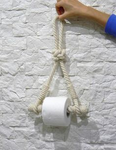 a person holding a roll of toilet paper on a rope attached to a brick wall