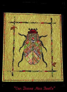 a yellow and black quilted wall hanging with a beetle on it's side