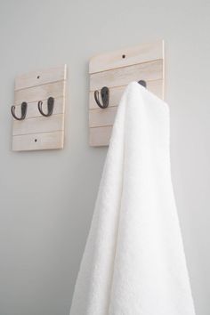 two towel hooks are mounted on the wall next to a white towel hanging from a hook