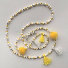 a white and yellow beaded necklace with tassels on the end, along with two small beads