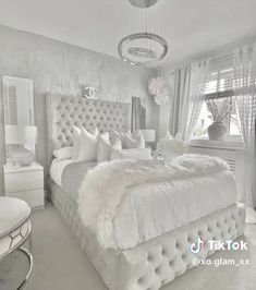 a large white bed sitting in a bedroom next to a window