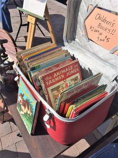 an open suitcase filled with books on top of a wooden table next to a sign that says flea market tips