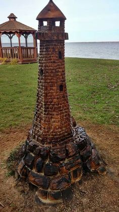 a tower made out of bricks sitting on top of a grass covered field next to the ocean