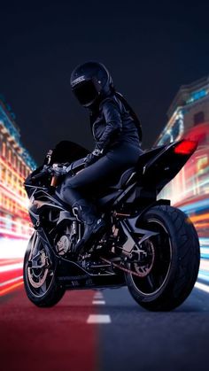 a man riding on the back of a motorcycle down a street at night with motion blurs behind him