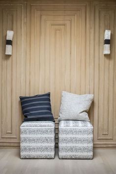 two white and blue pillows sitting next to each other on top of a wooden floor