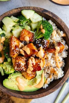 a wooden bowl filled with rice, broccoli and chicken