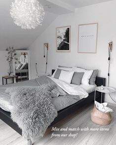 a bedroom with white walls and wood flooring is decorated in black and white tones