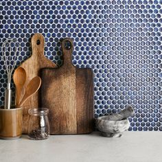 a wooden cutting board sitting on top of a counter next to utensils and spoons