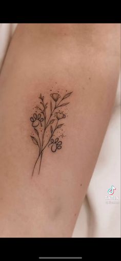 a small flower tattoo on the back of a woman's arm