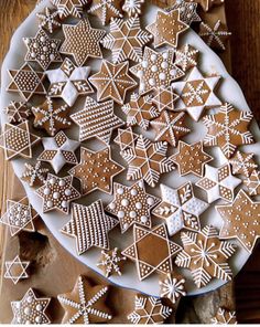 a white plate topped with lots of cut out gingerbread cookies next to a wooden table