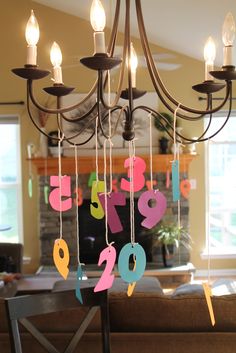 a chandelier with numbers hanging from it's arms in a living room