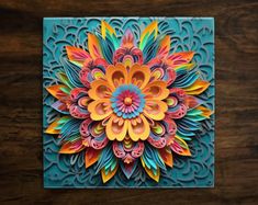 an intricately designed paper art piece on a wooden surface with blue and orange colors