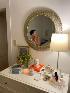 a woman is reflected in the mirror above a dresser with makeup and other items on it