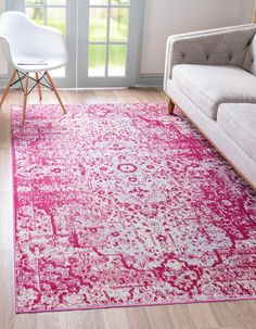 a living room with a white couch, pink rug and chair in front of the window