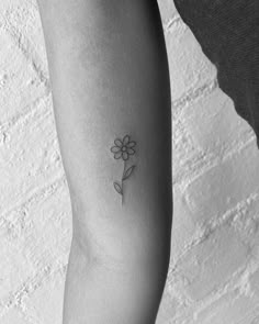 a black and white photo of a woman's arm with a flower tattoo on it