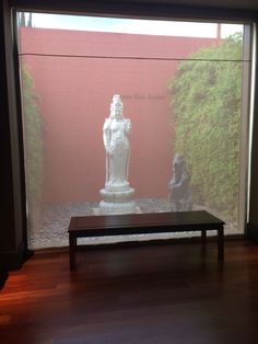 a bench sitting in front of a window with a statue on it's side