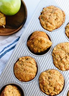 apple muffins in a muffin tin next to an apple