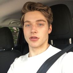 a young man sitting in the back seat of a car with his head turned to the side